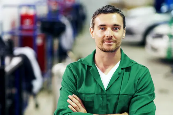 Angestellter mit einer Mechanikerwerkstatt im Hintergrund