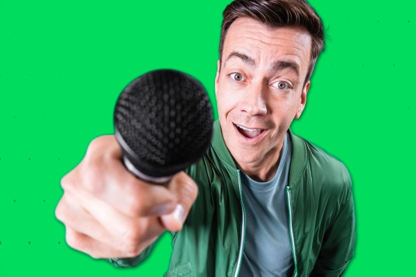 Tobias Wobbe hält Mikrofon vor grünem Hintergrund