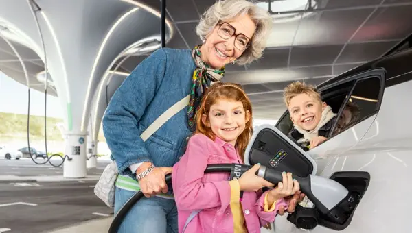 Frau mit zwei Kindern beim Aufladen eines E-Autos Frau mit zwei Kindern beim Aufladen eines E-Autos