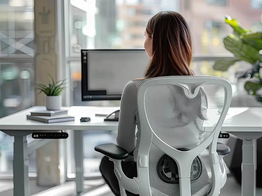 Frau sitzt im Schreibtischstuhl am Schreibtisch