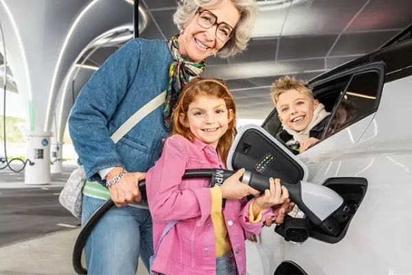Frau mit zwei Kindern beim Aufladen eines E-Autos Frau mit zwei Kindern beim Aufladen eines E-Autos