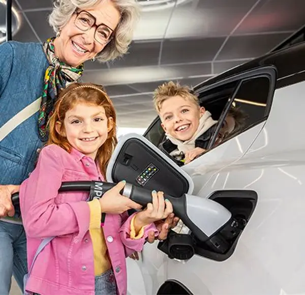 Frau mit zwei Kindern beim Aufladen eines E-Autos