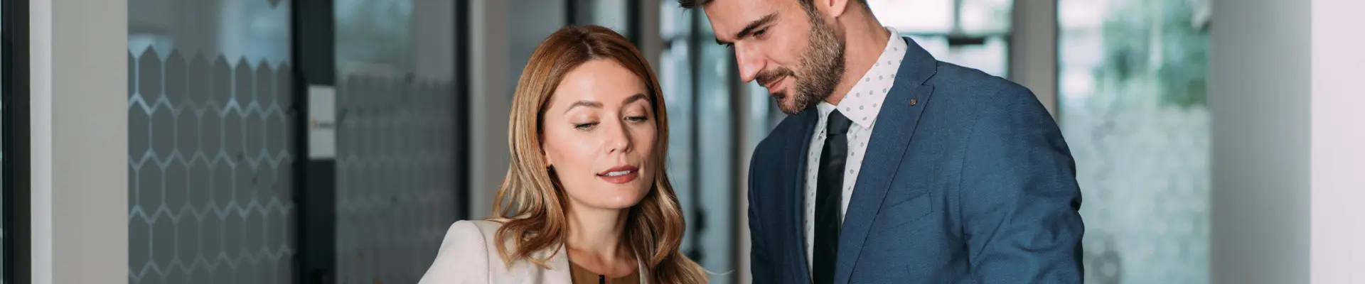 Two colleagues discussing and reviewing content on a tablet held by the woman in a business setting.