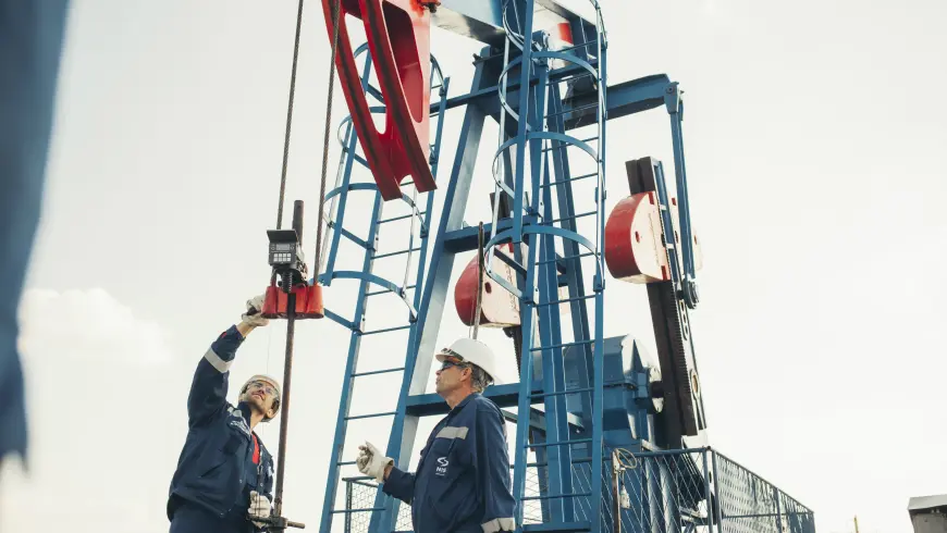 Two men in overalls and safety gear handling a drill