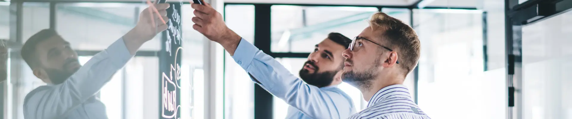Two men discussing content on a whiteboard in a business setting.