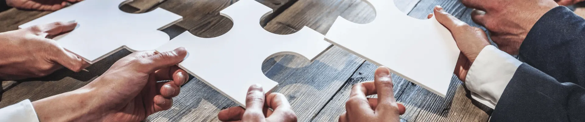 People holding puzzle pieces, trying to fit them together.