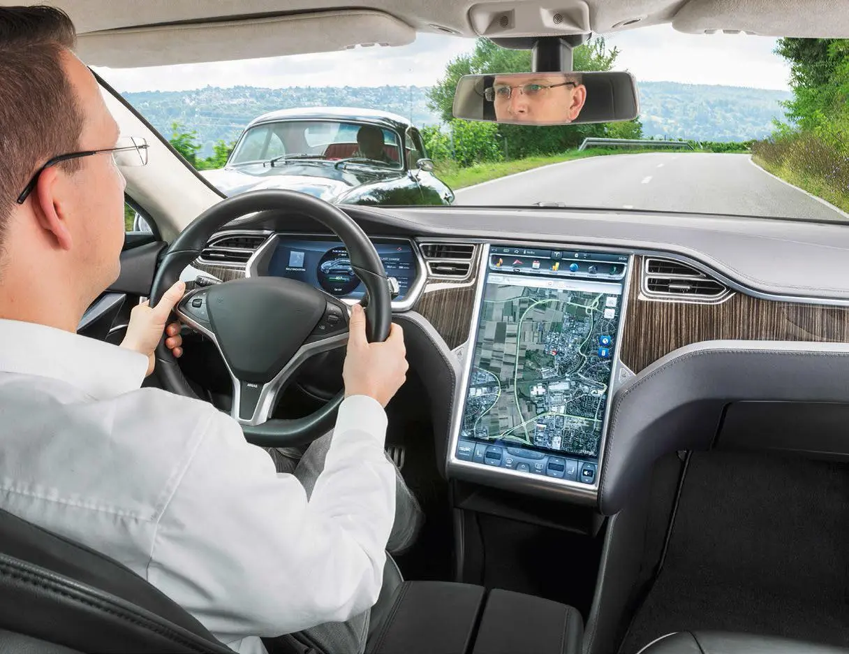 Hombre sentado en un coche detrás del volante.