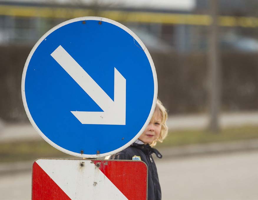 Niño detrás de un letrero de la calle