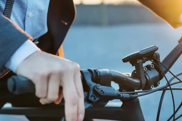 Zbliżenie na dłonie mężczyzny jadącego na rowerze elektrycznym, na tle zachodzącego słońca Zbliżenie na dłonie mężczyzny jadącego na rowerze elektrycznym, na tle zachodzącego słońca