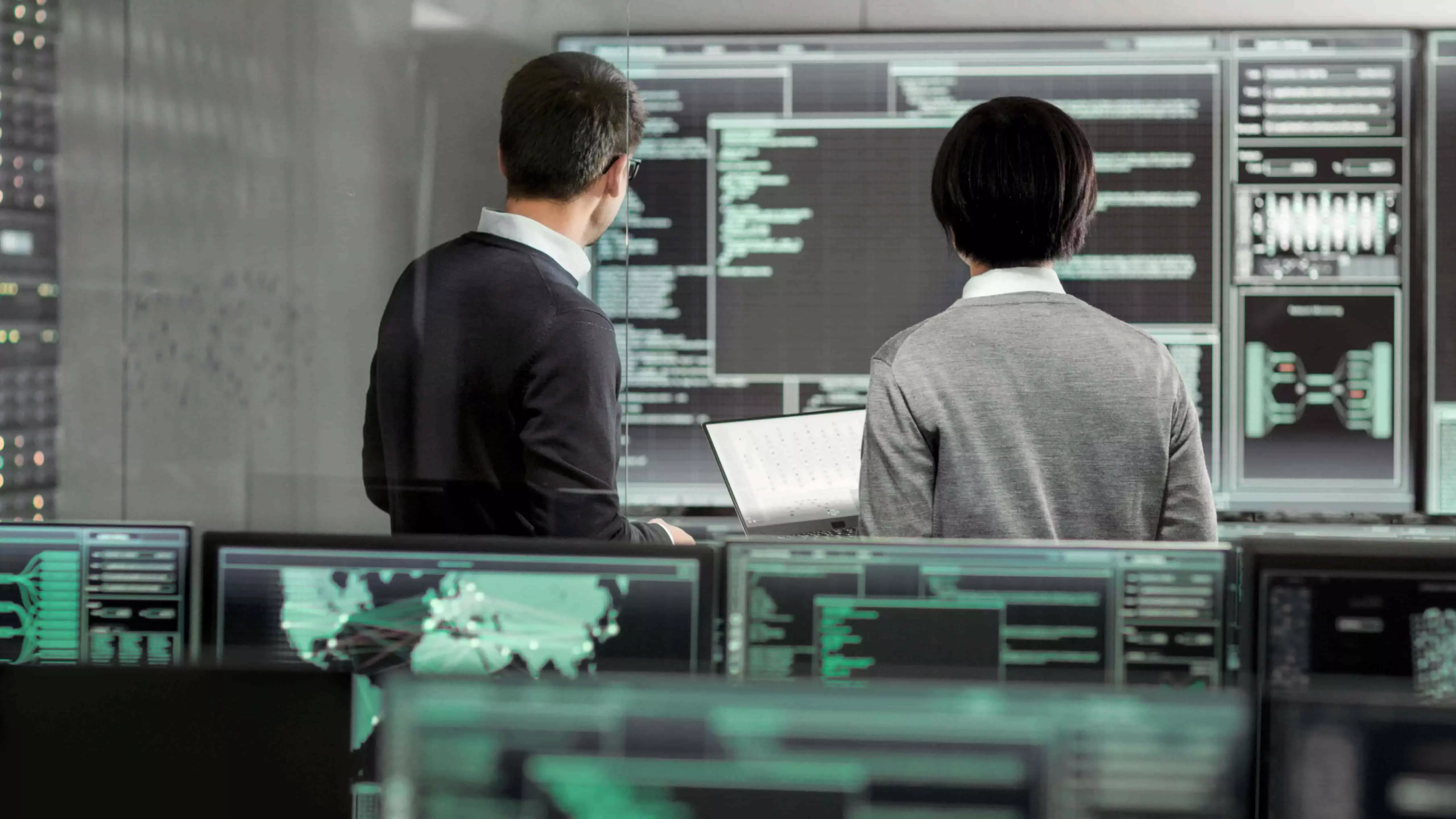 Dwóch mężczyzn analizujących dane na monitorach, symbolizujących audyt ochrony danych
