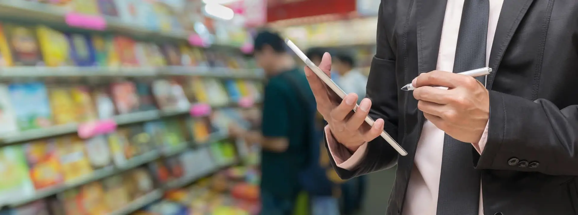 Mężczyzna w garniturze znajdujący się w sklepie, piszący w notatniku, symbolizujący badanie i certyfikację wyrobów