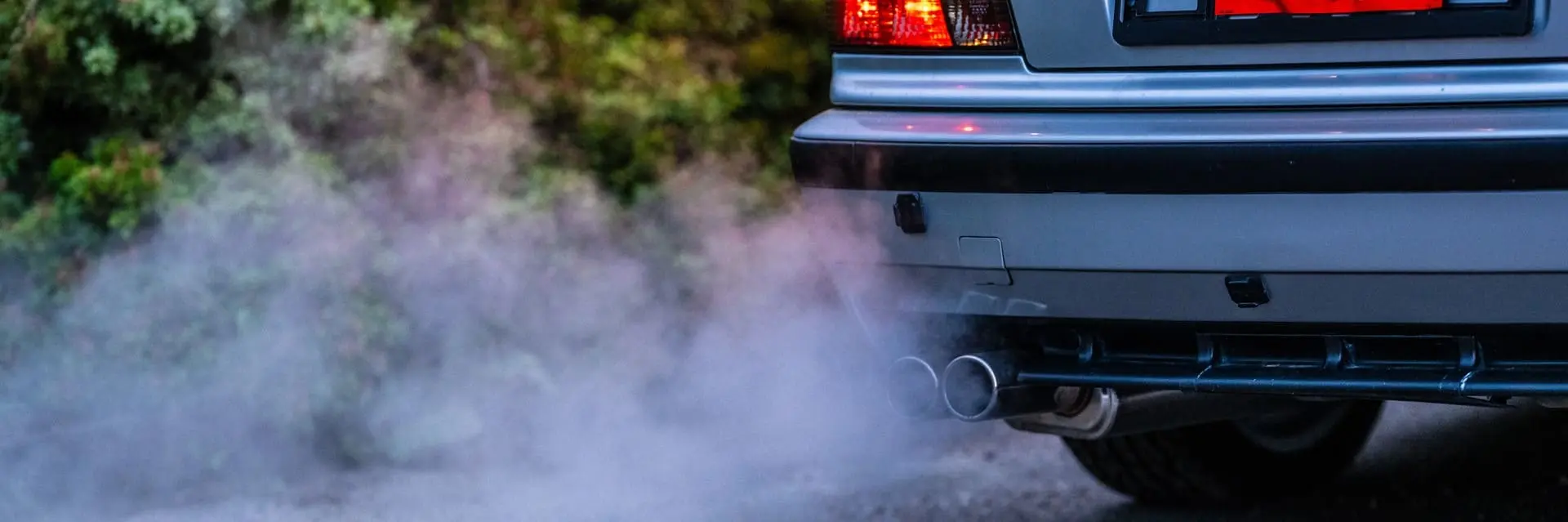 Emisja spalin z rury wydechowej samochodu, symbolizująca usługi badania hałasu i emisji spalin
