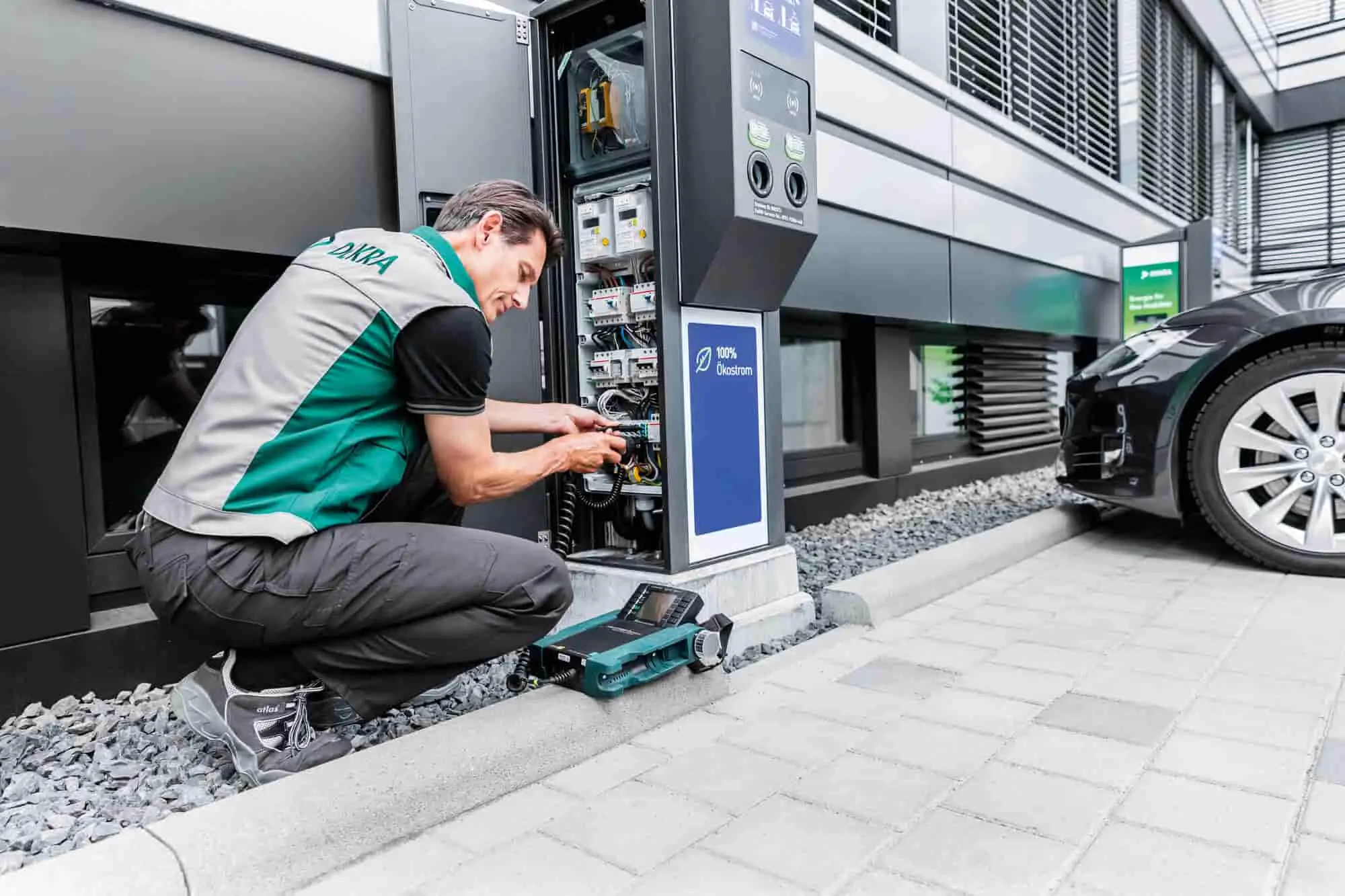 Technik DEKRA kontrolujący stację ładowania pojazdu elektrycznego.