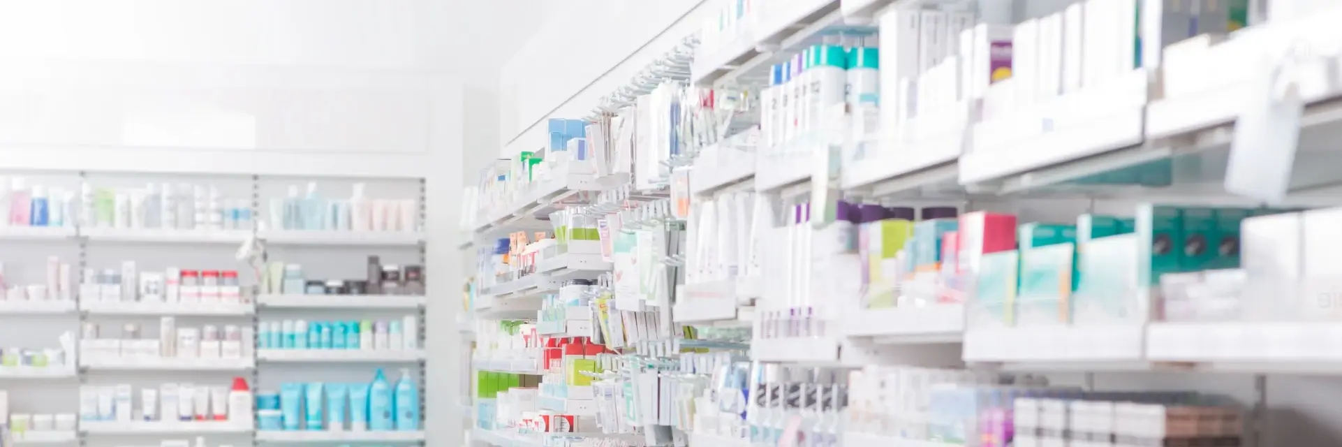 Leki znajdujące się na półkach w aptece, symbolicujące certyfikację GDP