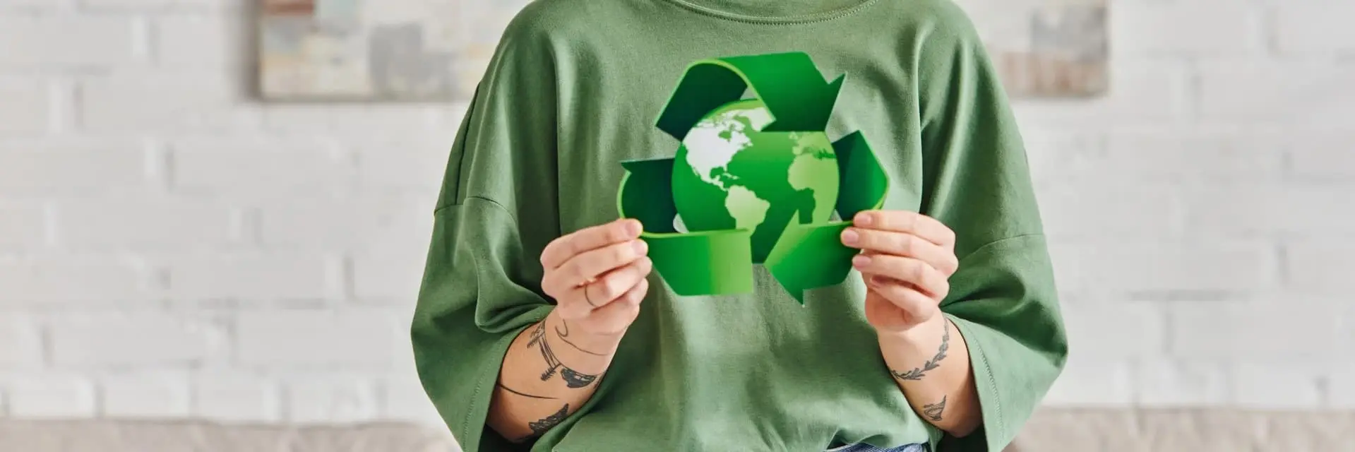 Kobieta trzymająca w dłoniach zieloną kulę ziemską, otoczoną znakiem recyklingu, co symbolizuje certyfikację ISO 14001