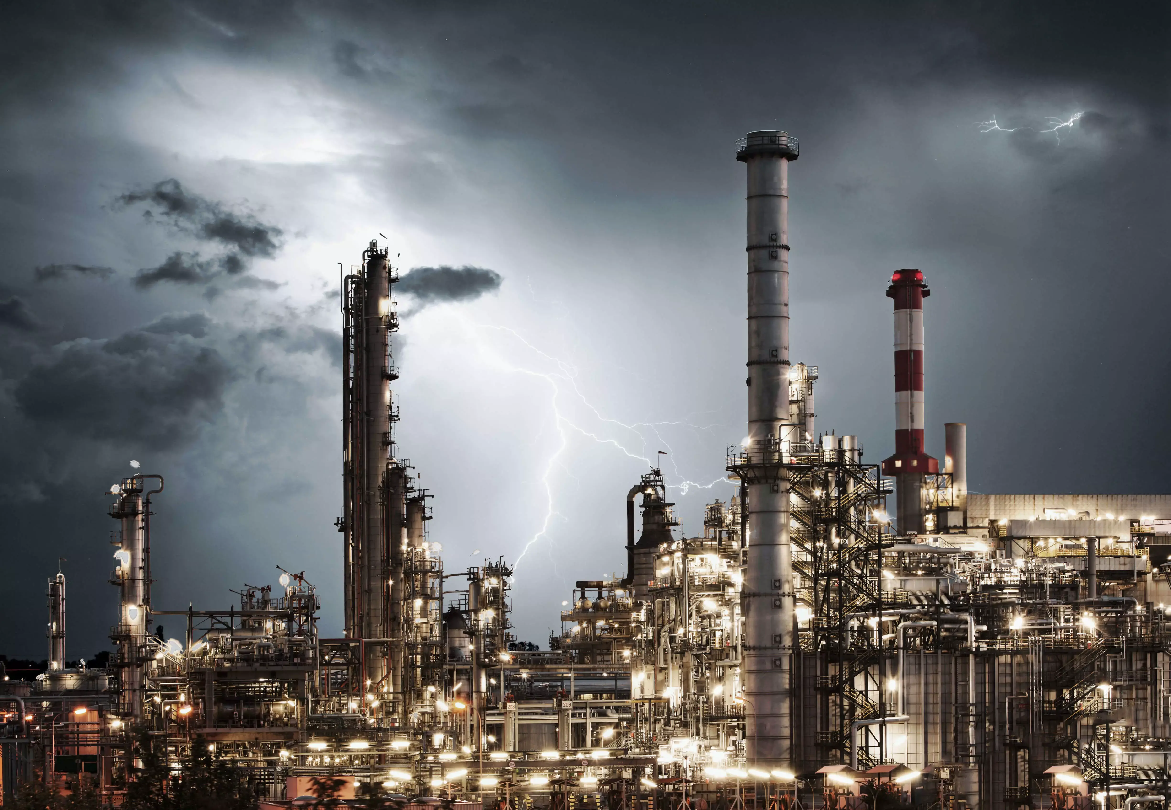 Zakład przemysłowy na tle burzowego nieba, symbolizujący potrzebę zabezpieczenia procesów biznesowych zgodnie z normą ISO 22301