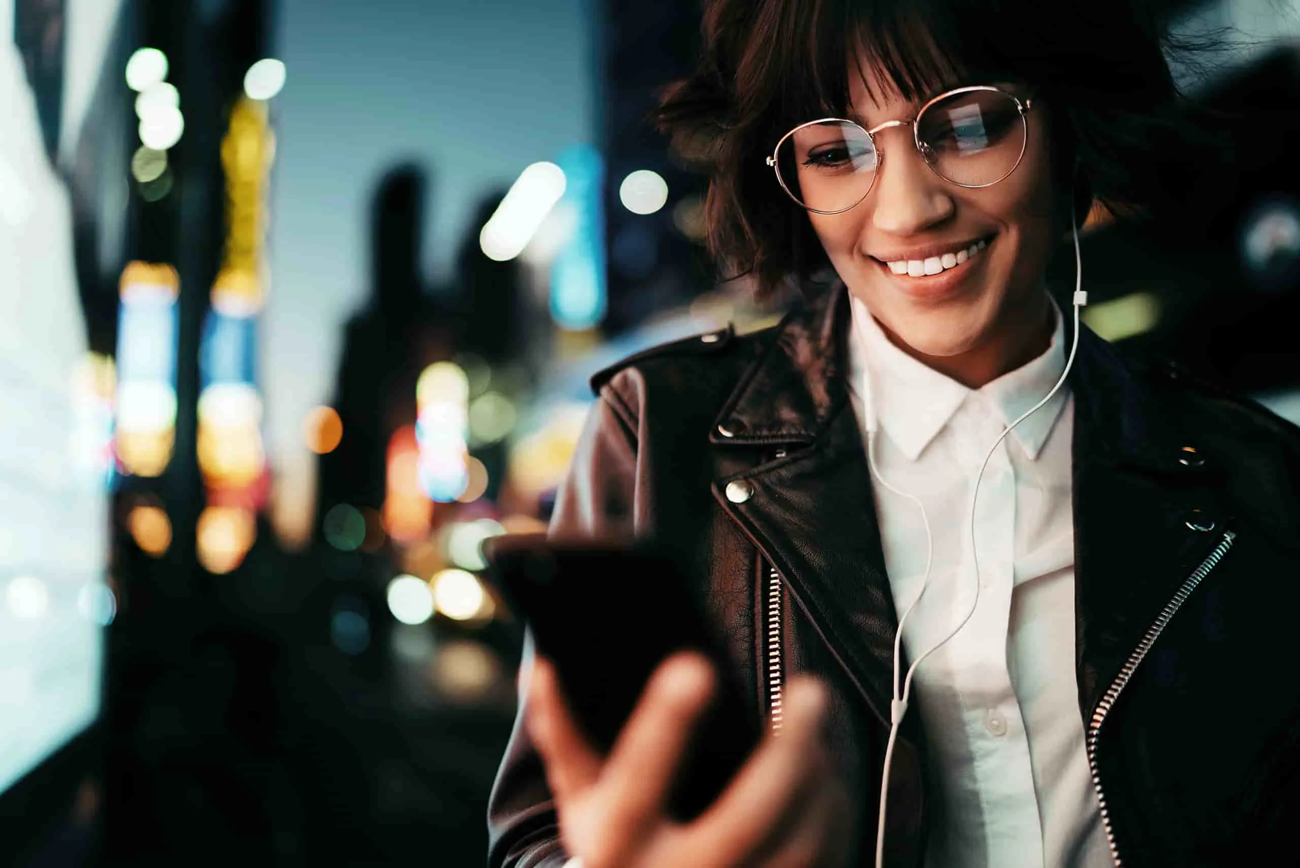 Osoba uśmiechnięta, korzystająca ze smartfona, symbolizująca bezpieczeństwo informacji w usługach chmurowych zgodnie z certyfikacjami ISO 27017 i ISO 27018