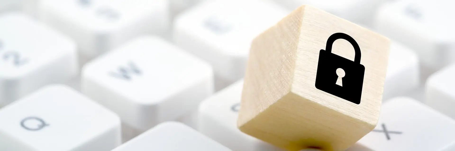 Drewniana kostka z symbolem zamkniętej kłódki, znajdująca się na klawiaturze, symbolizująca certyfikację ISO 27701 Drewniana kostka z symbolem zamkniętej kłódki, znajdująca się na klawiaturze, symbolizująca certyfikację ISO 27701