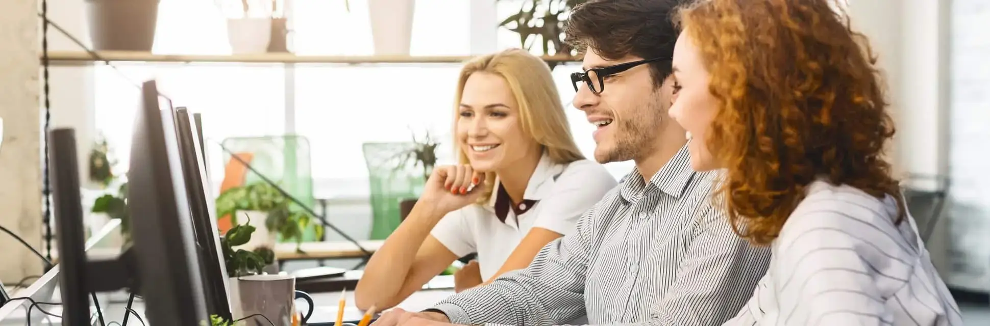 Pracownicy w biurze patrzą na ekran komputera, który przedstawia symbol certyfikacji ISO 9001