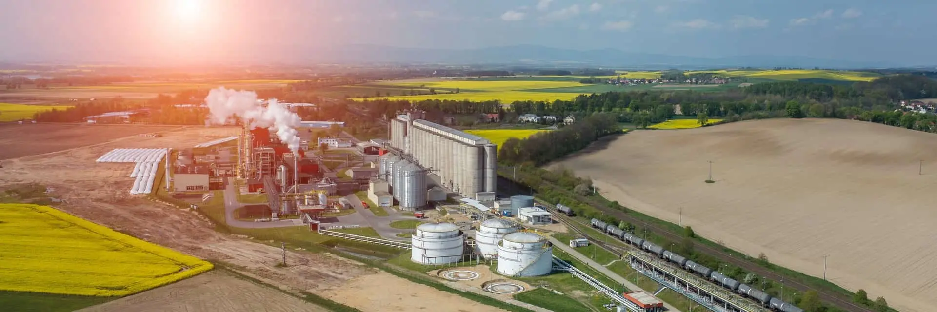 Zachód słońca nad fabryką biopaliw, co symbolizuje certyfikację KZR INiG - paliwa z biomasy dla energetyki