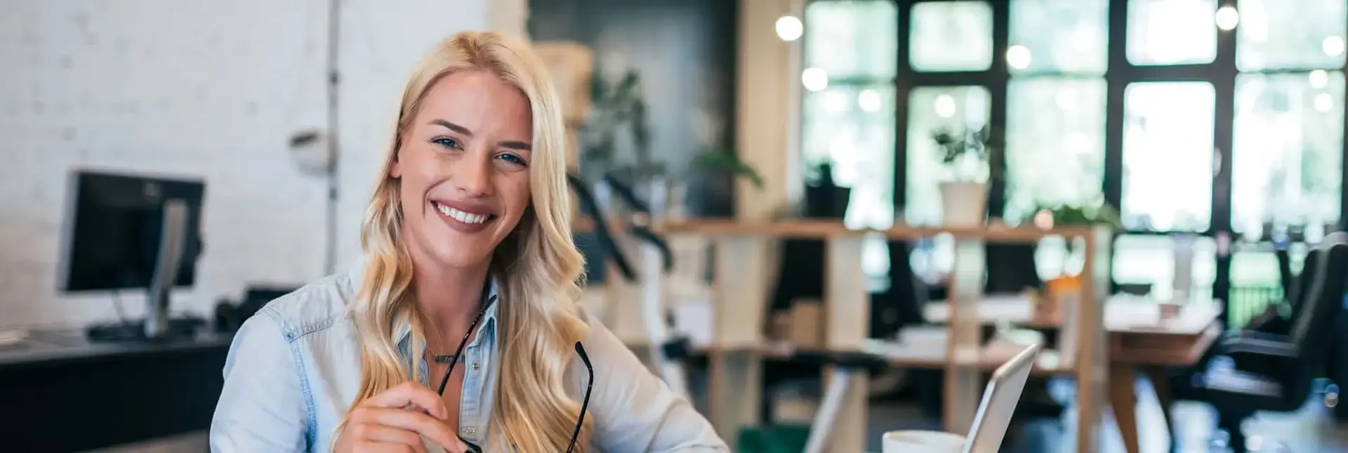 Kobieta z szerokim uśmiechem na twarzy, pracująca w biurze, symbolizująca certyfikację osób