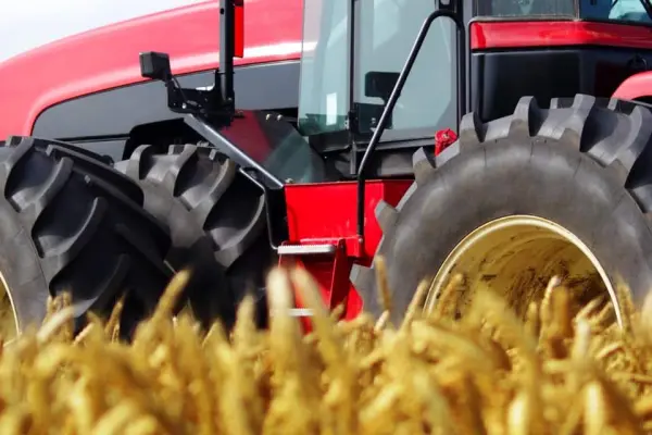 Czerwony traktor pracujący w polu, symbolizujący certyfikację REDcert Czerwony traktor pracujący w polu, symbolizujący certyfikację REDcert