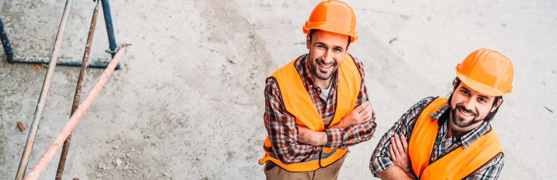 Dwóch mężczyzn w kamizelkach odblaskowych i kaskach, pracujących na budowie, symbolizujących certyfikację SCC