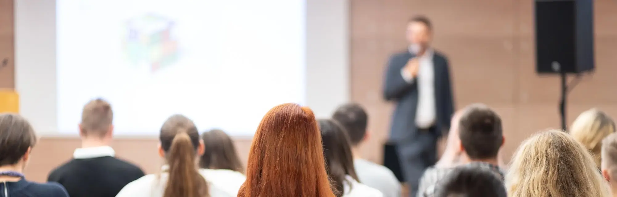 Prelegent przemawiający w sali konferencyjnej przed tłumem ludzi, symbolizujący certyfikację SUS 3.0