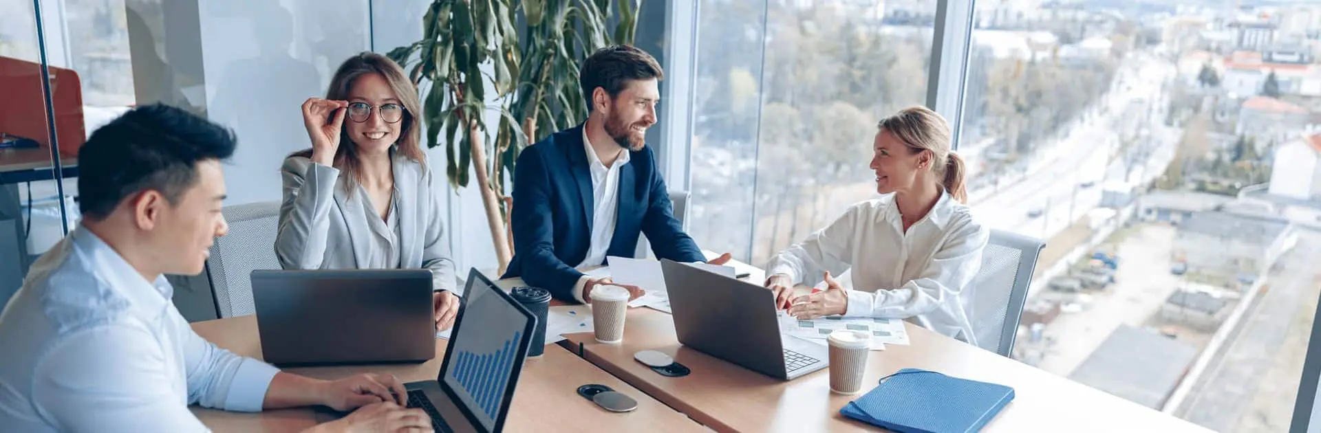 Ludzie pracujący w biurze, siedzący przy biurkach, symbolizujący certyfikację systemów zarządzania 