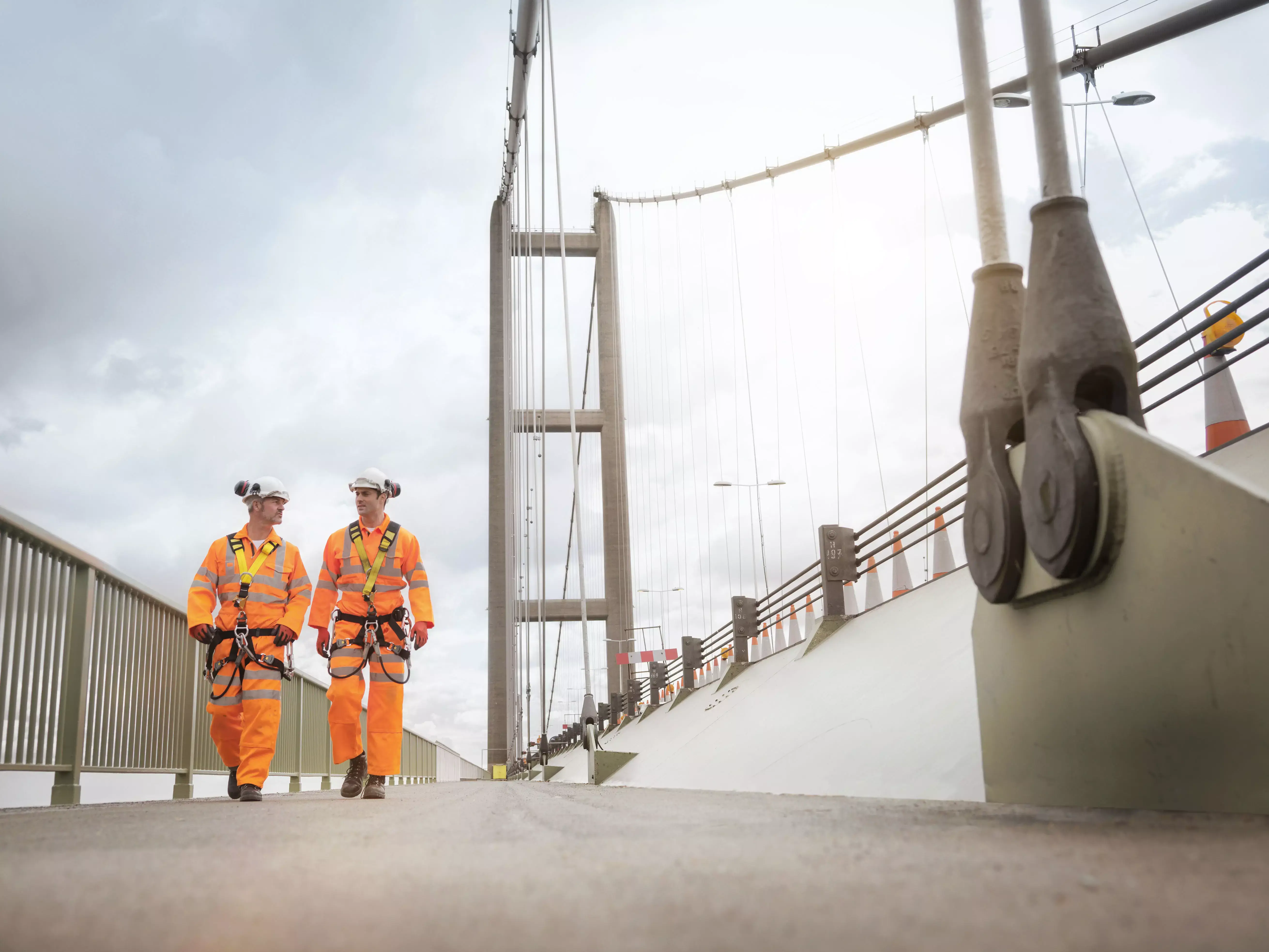 Dwóch pracowników w odzieży ochronnej na moście, symbolizujących zarządzanie bezpieczeństwem i higieną pracy zgodnie z normą ISO 45001