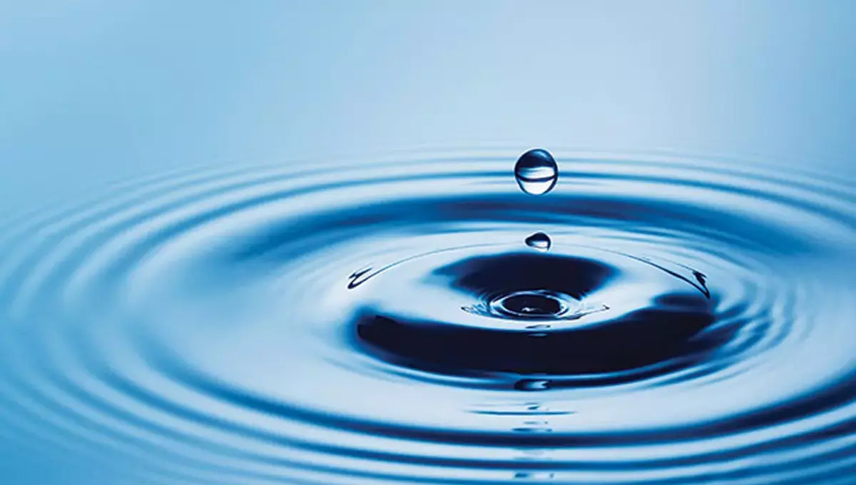 Kropla wody spadająca na powierzchnię tworzy kręgi na spokojnej tafli.