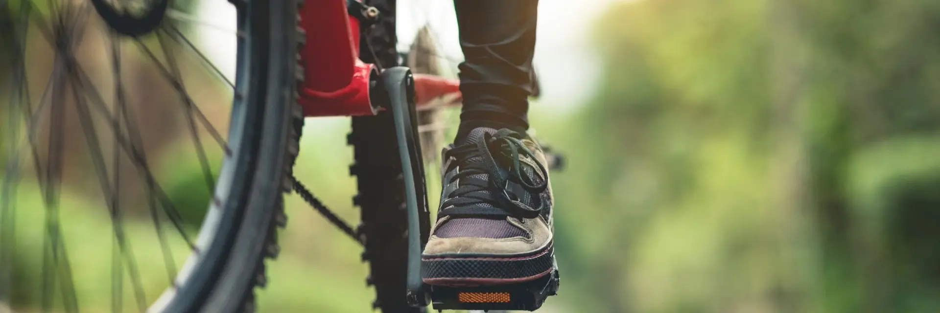 Zbliżenie na stopę na pedale osoby jadącej na rowerze w otoczeniu lasu Zbliżenie na stopę na pedale osoby jadącej na rowerze w otoczeniu lasu