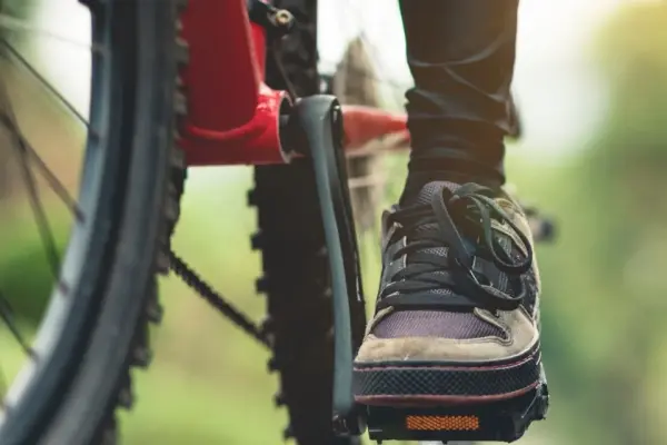 Zbliżenie na stopę na pedale osoby jadącej na rowerze w otoczeniu lasu Zbliżenie na stopę na pedale osoby jadącej na rowerze w otoczeniu lasu