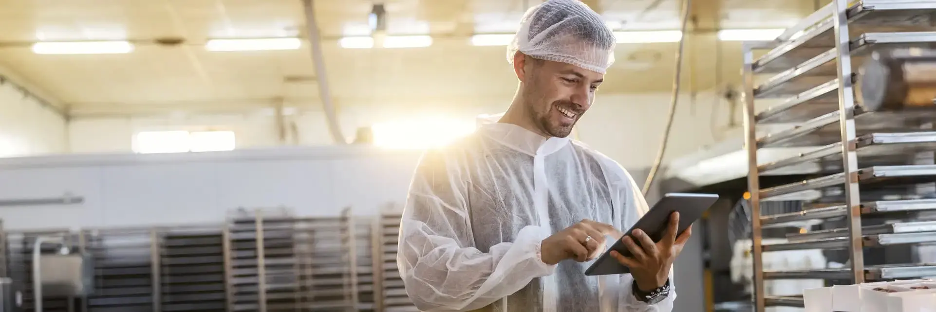 Pracownik zakładu spożywczego w odzieży ochronnej wykonujący kontrolę jakości na tablecie, zgodność z wymogami IFS Food. Pracownik zakładu spożywczego w odzieży ochronnej wykonujący kontrolę jakości na tablecie, zgodność z wymogami IFS Food.