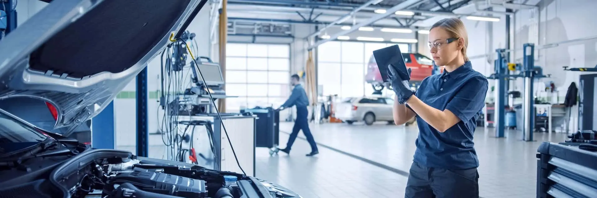 Inżynierka w laboratorium testowym sprawdzająca dane na tablecie w trakcie inspekcji pojazdu