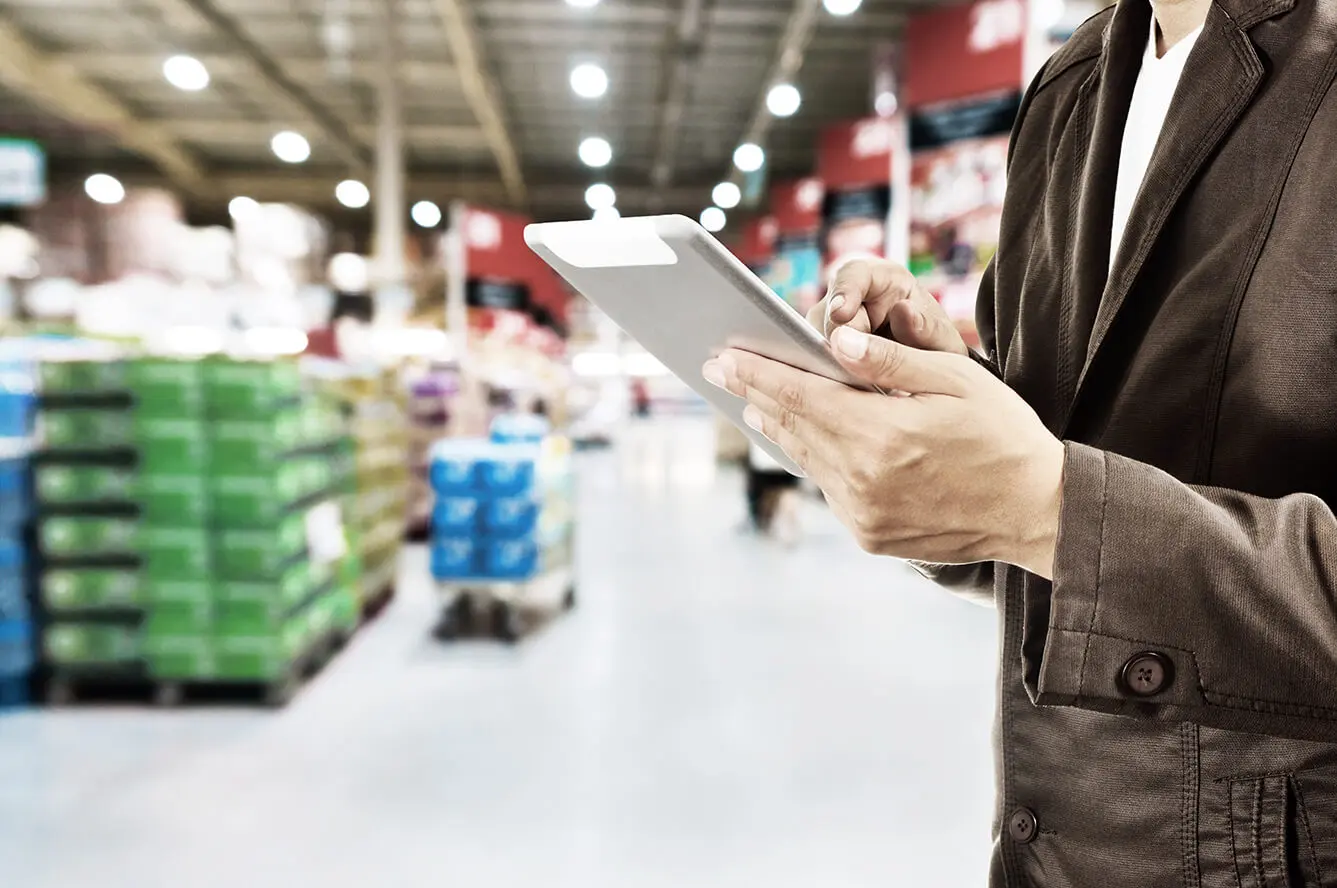Mann im Supermarkt tippt auf einem Tablet