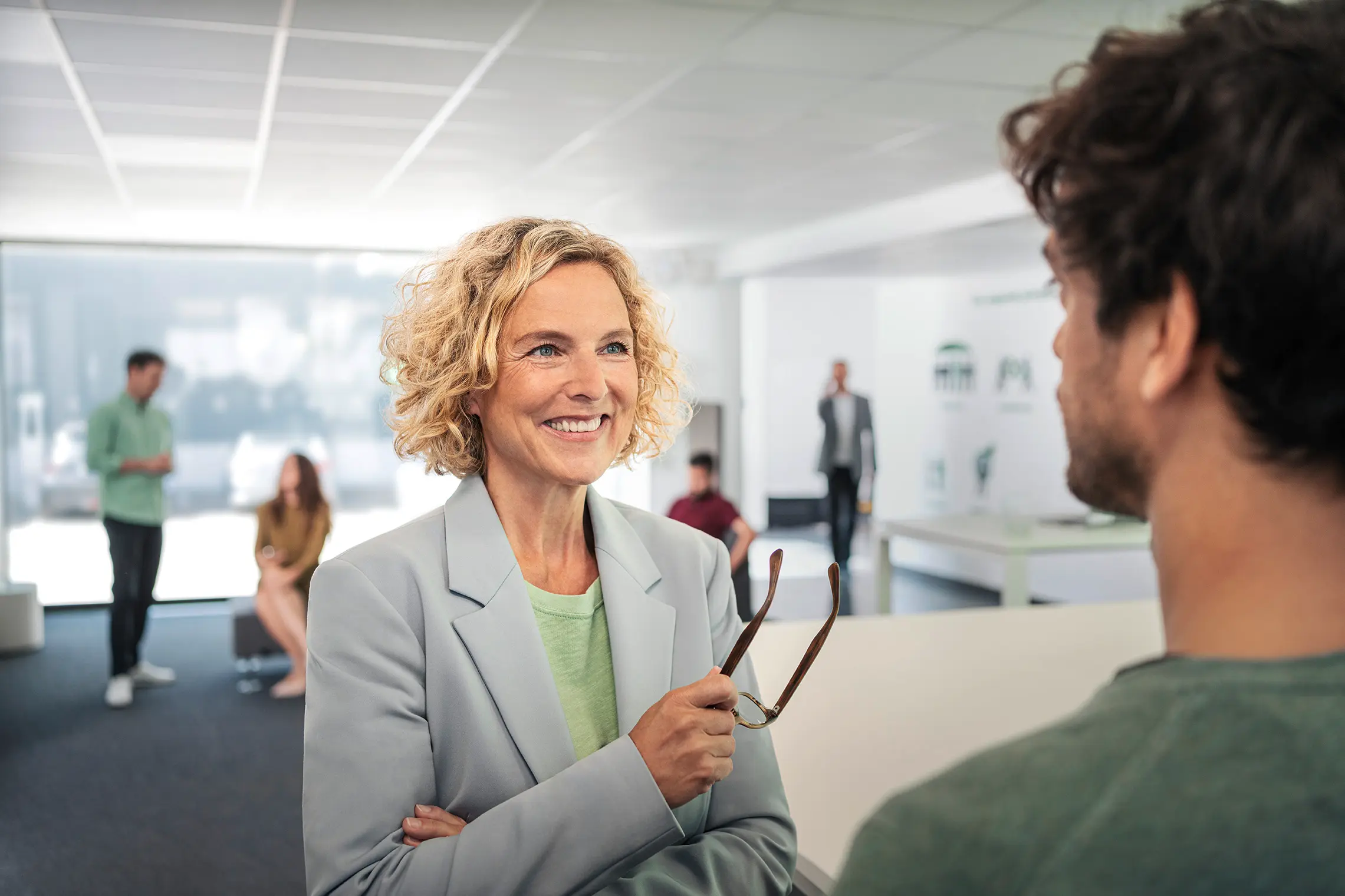blonde Frau in Gespräch mit Mann in einem Büroraum blonde Frau in Gespräch mit Mann in einem Büroraum