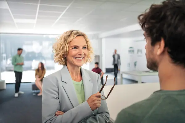 blonde Frau in Gespräch mit Mann in einem Büroraum blonde Frau in Gespräch mit Mann in einem Büroraum