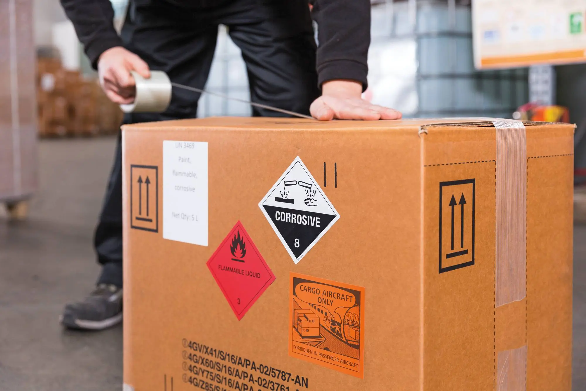 Mann klebt Box mit Gefahrgutinhalt zu Mann klebt Box mit Gefahrgutinhalt zu