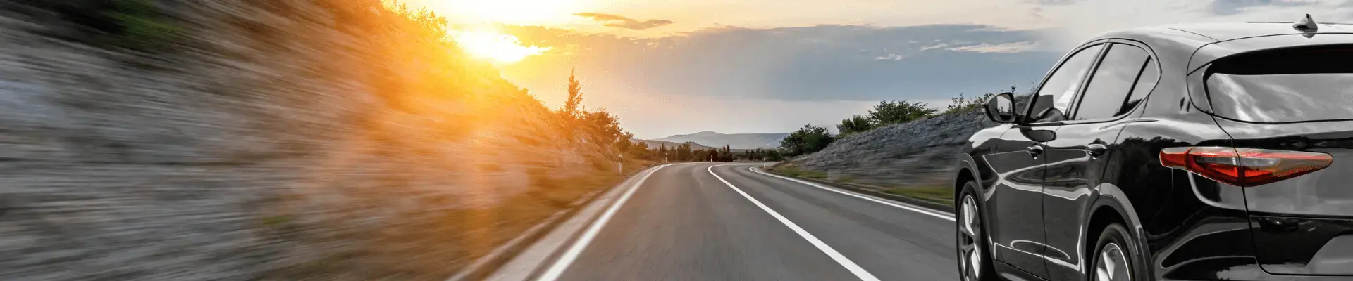 Ein graues Auto fährt auf einer Straße, umgeben von einer Naturlandschaft Ein graues Auto fährt auf einer Straße, umgeben von einer Naturlandschaft