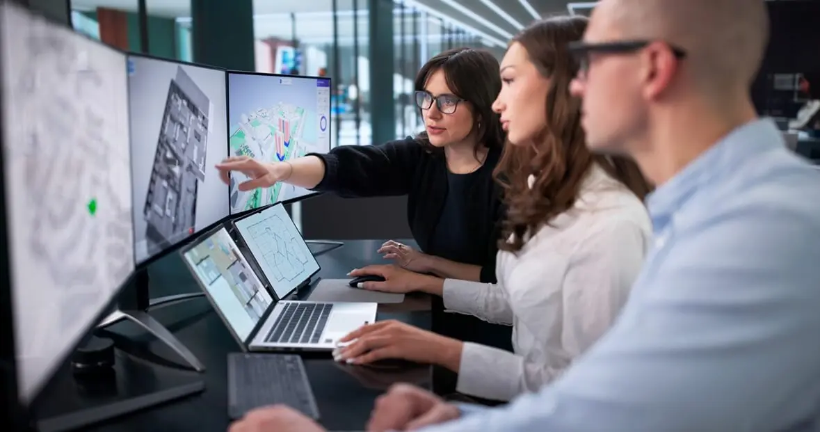 Three people sitting in front of three computer screens, checking analyses. Three people sitting in front of three computer screens, checking analyses.