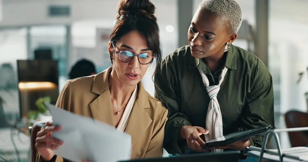 Two women looking at a piece of paper. Two women looking at a piece of paper.