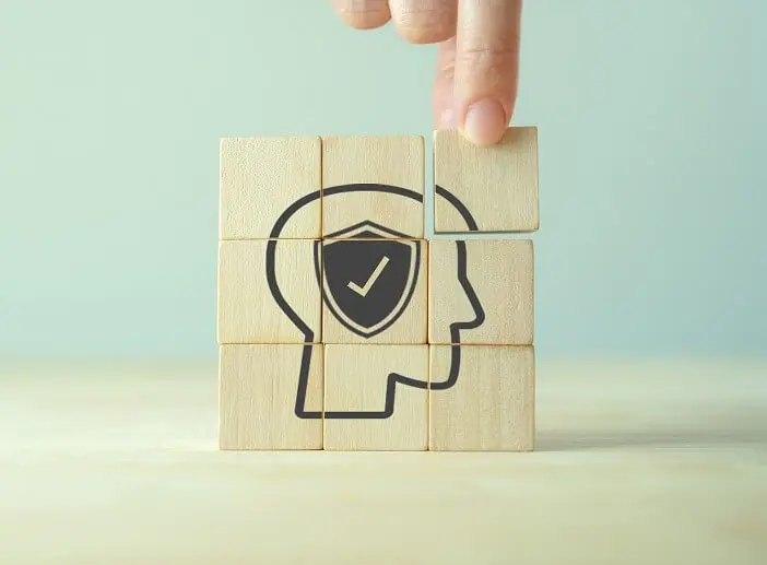 En hand som bygger en bild av av ett huvud med kvadratiska träkuber. En hand som bygger en bild av av ett huvud med kvadratiska träkuber.