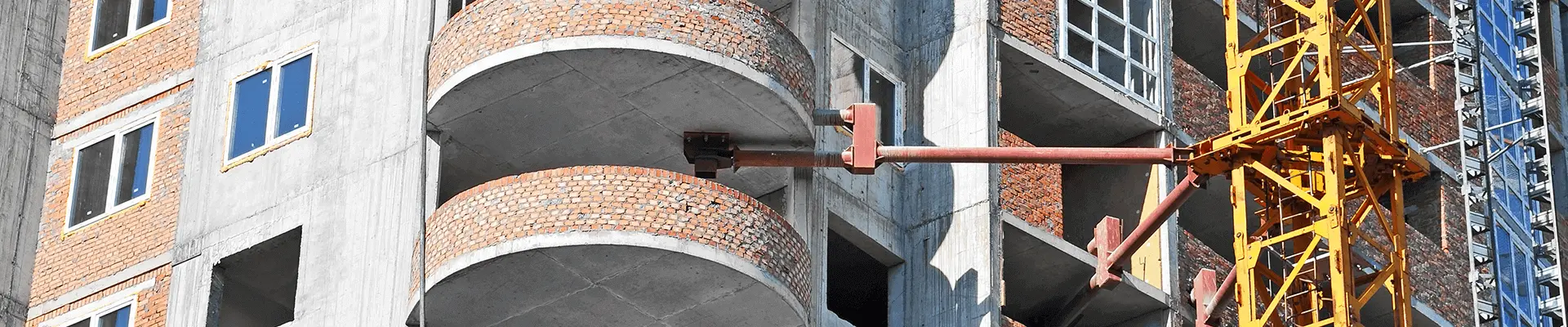 En fastighet med balkonger som byggs i betong och en byggställning utanför fasaden.