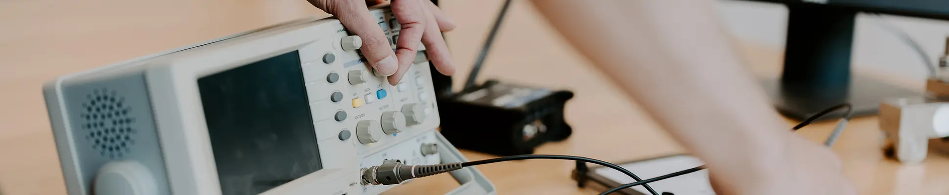 En person sitter vid ett skrivbord och använder en maskin för beräkning och simulering genom att vrida på olika komponenter på maskinen. 