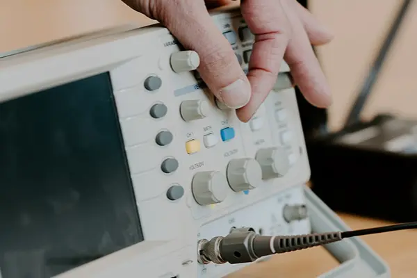 En person sitter vid ett skrivbord och använder en maskin för beräkning och simulering genom att vrida på olika komponenter på maskinen. 