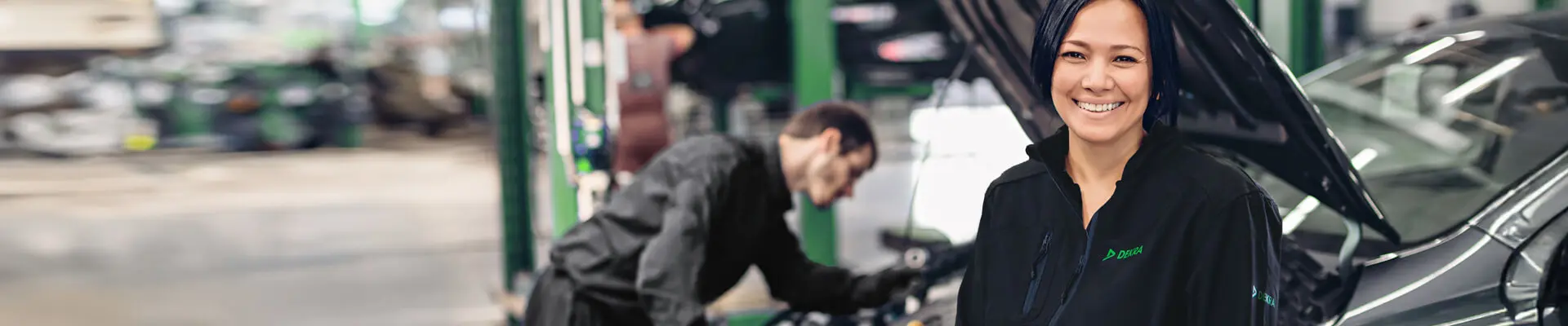  En kvinna sitter framför en bil, med en skylt som läser "DEKRA", som visar upp hennes engagemang med biltjänster.