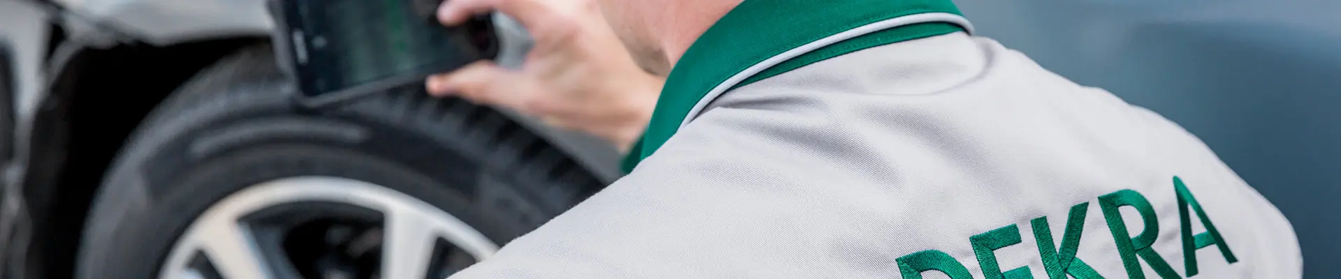 En man i arbetskläder seende bakifrån med en bil framför. En man i arbetskläder seende bakifrån med en bil framför.