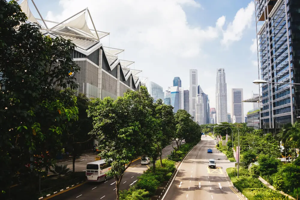 Read more here A road through a big city with modern buildings and lots of greenery.