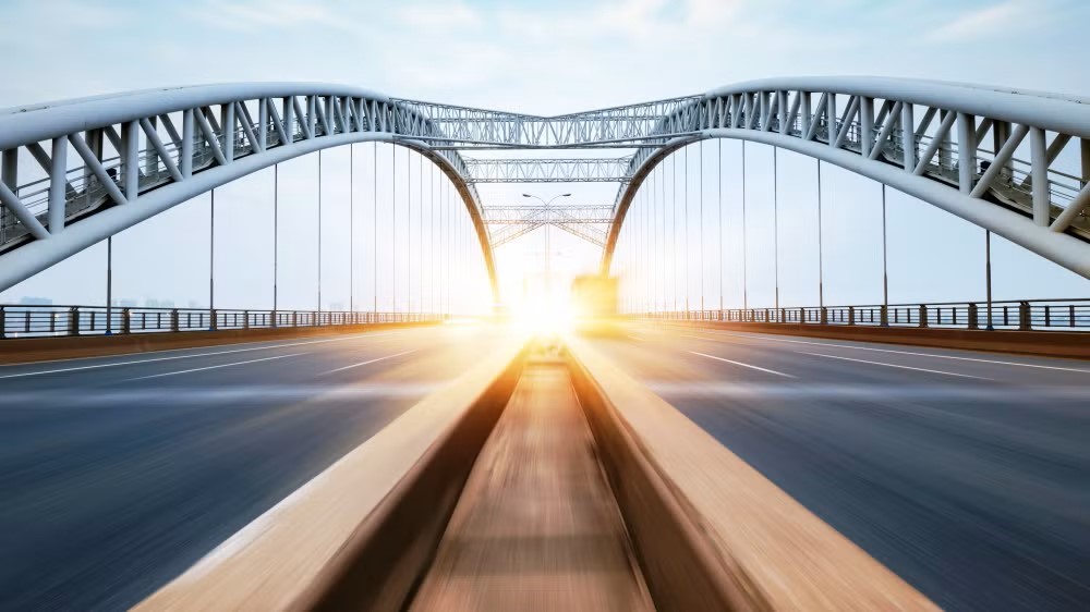 En bild som genom förstapersonperspektiv visar en rak väg över en bro. Bilden symboliserar en stabil väg framåt för DEKRA.